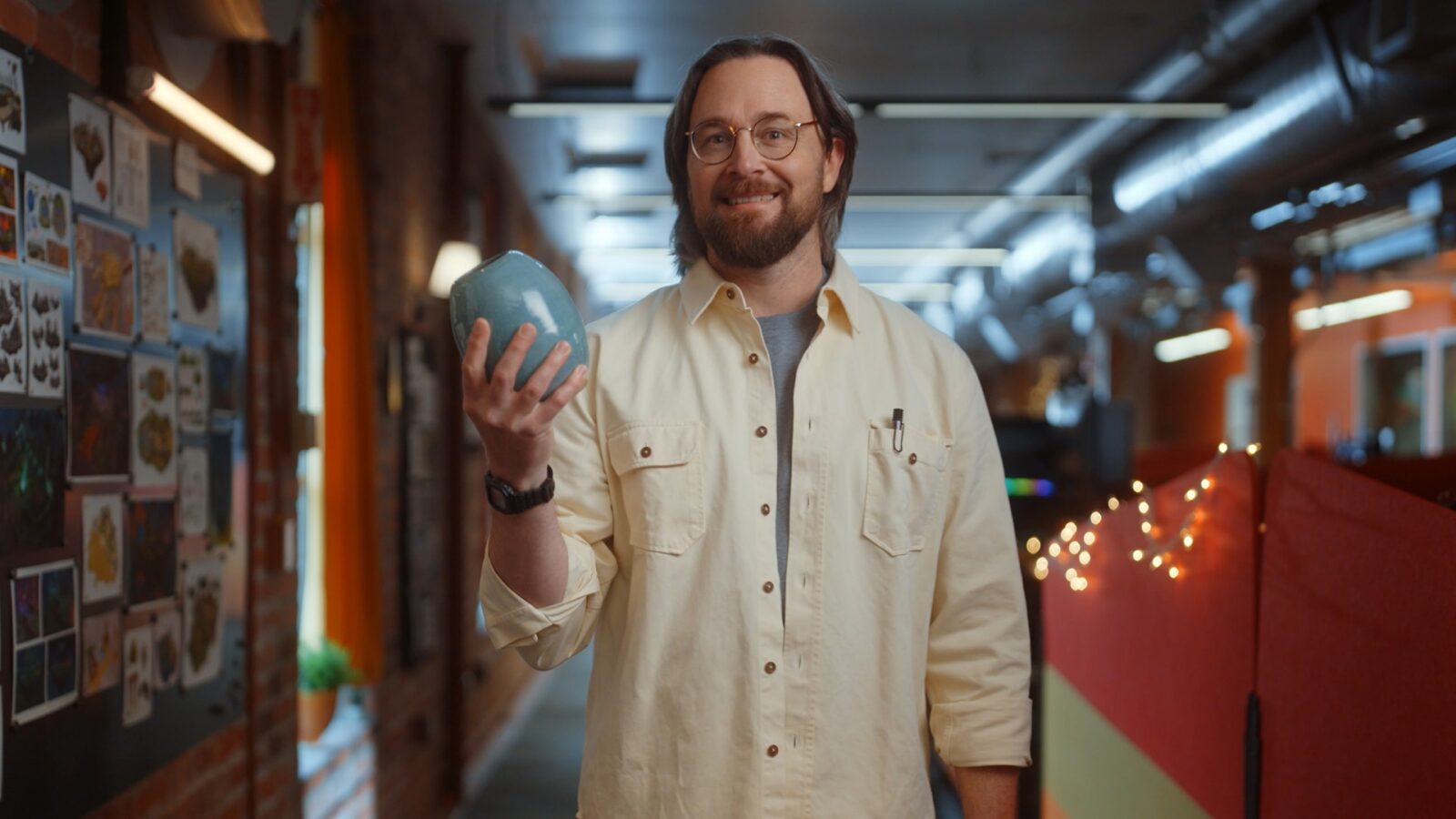 Photo of man holding a small piece of pottery and smiling